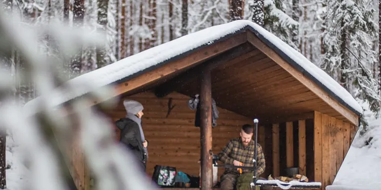 Nainen ja mies juovat kahvia laavulla.