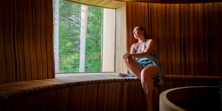 A woman relaxing in the round steam room of Serlachius Art Sauna.