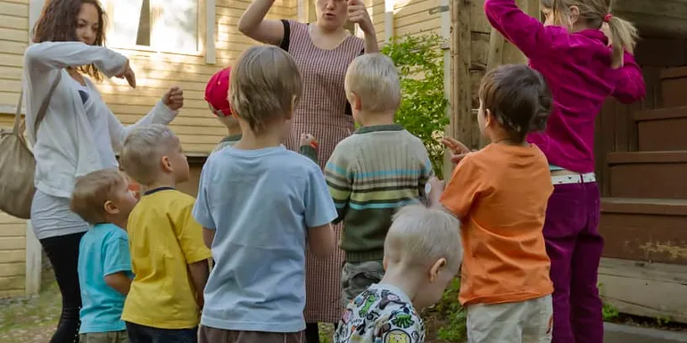 Lapset seisovat oppaan ympärillä Amurin pihalla.