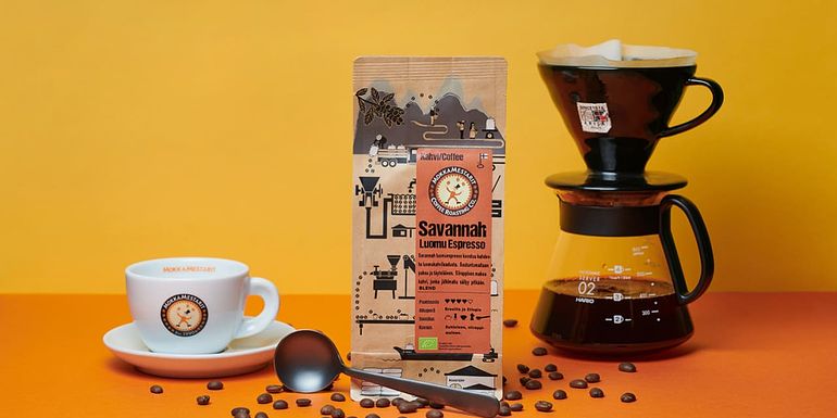 Kahvipaketti, kahvikuppi ja Harion V60 -käsiuuttomenetelmällä tippumassa kahvia