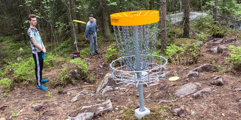 Henkilöt heittävät frisbeegolfia maaliin.