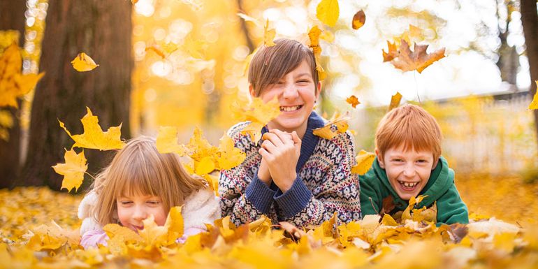 Three children playing with leaves