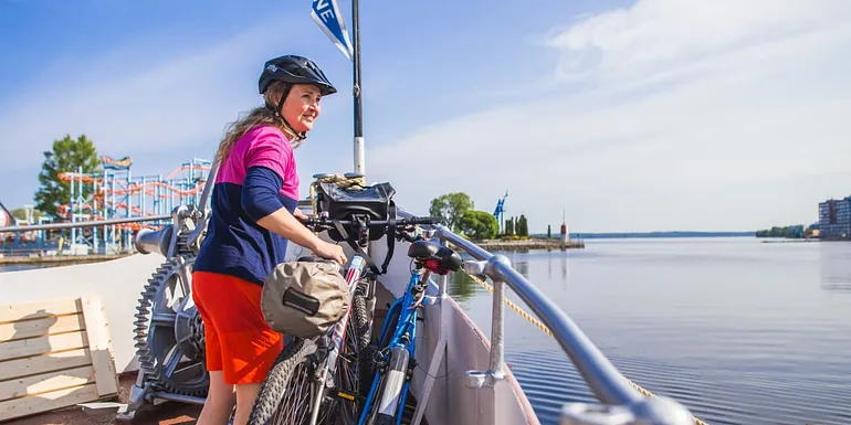 Nainen polkupyöräretkellä, osa matkasta taittuu laivalla.
