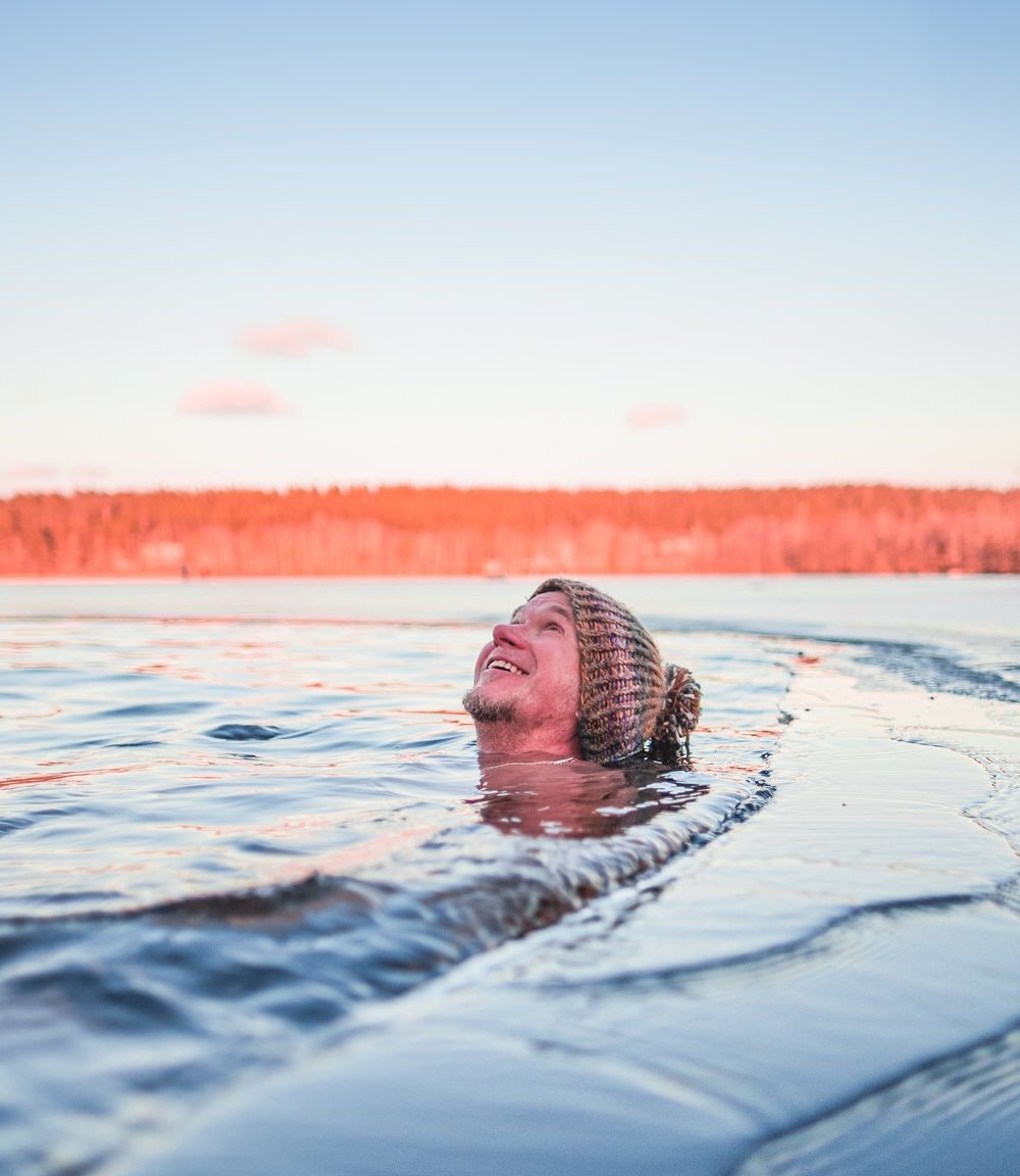 A man winter swimming with a woollen hat on
