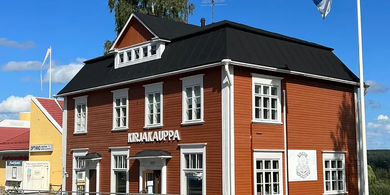 Suomen vanhimpia kivijalkakirjakauppoja Ruovedellä. Perinteinen punainen puutalo valkoisine yksityiskohtineen, jonka julkisivussa lukee 'KIRJAKAUPPA'. Vieressä liehuu Suomen lippu. Historiallinen kulttuurikohde ja eläväinen osa Ruoveden perintöä.