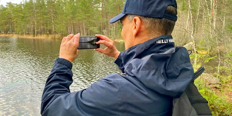 Mies valokuvaa järvimaisemaa.