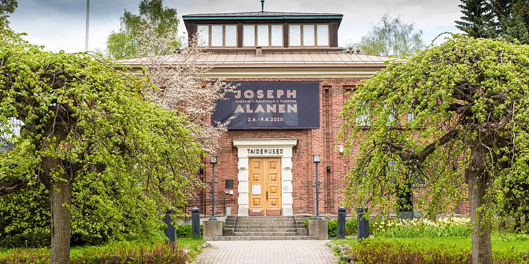 Punatiilinen museo puiden keskellä