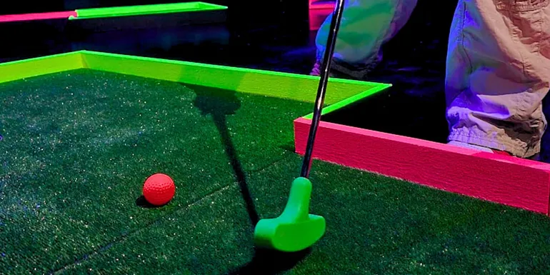A close-up of a minigolf club hitting a ball in Hohtogolf Tullintori