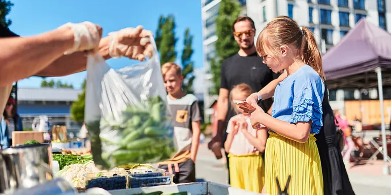 Aikuisia ja lapsia ostamassa herneitä torikauppiaalta