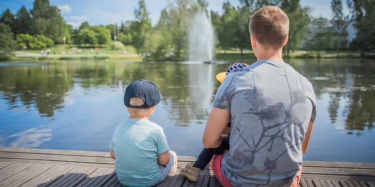 Family sitting on the pier in Sorsapuisto park.