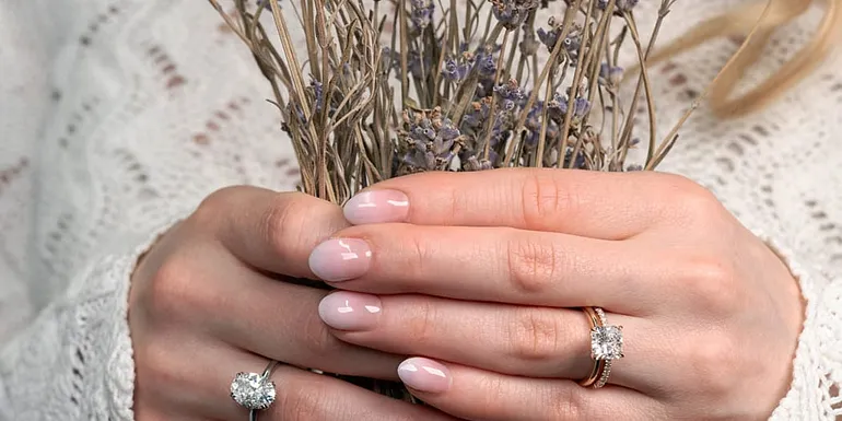 Kädet pitelevät kuivattua laventelikimppua, sormissa timanttisormukset.