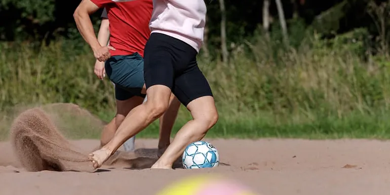 Ihmisiä pelaamassa beachfutista.