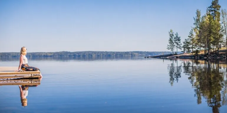 Henkilö katsomassa tyynelle järvelle laiturin päässä.