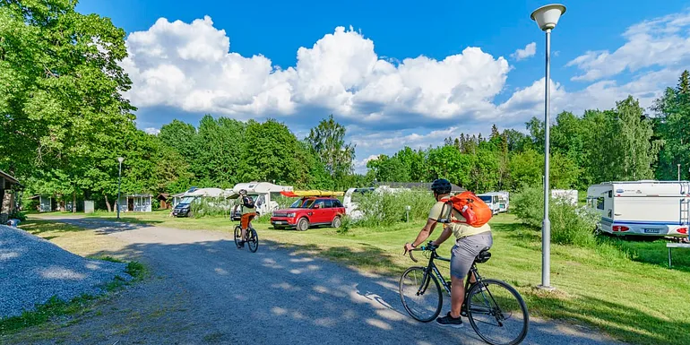 2 persons are cycling at the camping site.