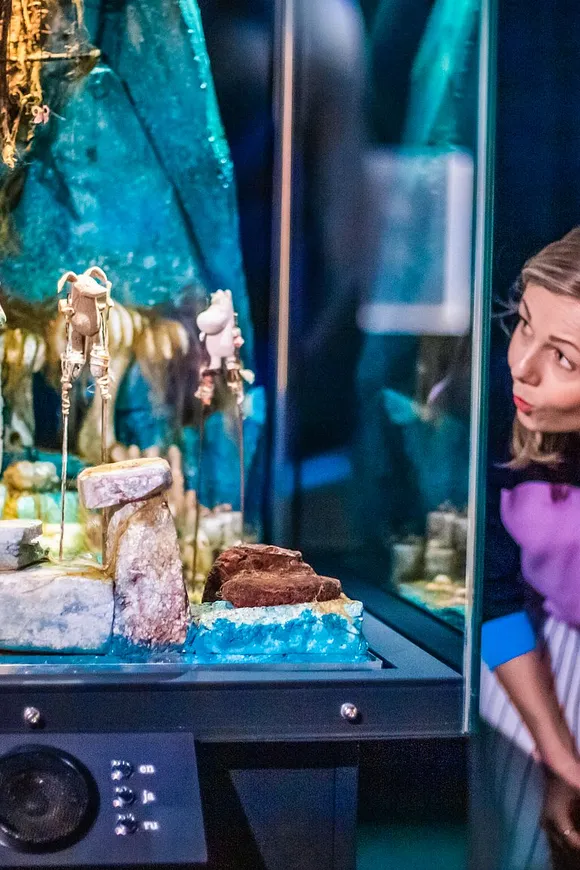 Kaksi henkilöä tutkii vitriinin sisältöä muumimuseossa